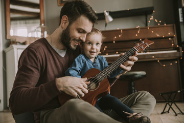 Father teaching daughter to play guitar at home