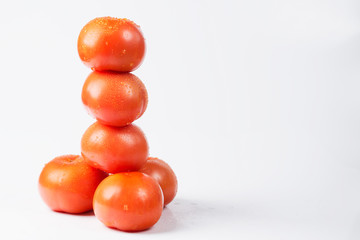 Red tomatoes on a white background with drops of water.