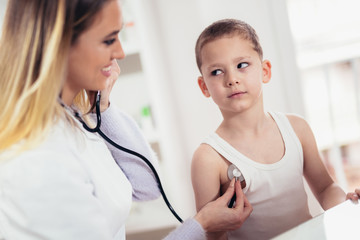 Doctor examining a little boy by stethoscope, medicine, healthcare, pediatry and people concept