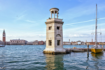 Daylight view to old stone tower near port with parked boats