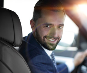 Handsome young man sitting in the front seat of a car looking at