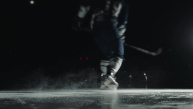 Ice Hockey player performing slap shot isolated on black background close up
