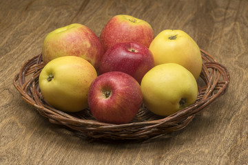 apples in a wicker plate on a wooden table
