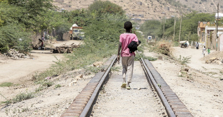 Fototapeta premium Dziecko idzie w dół torów kolejowych na pustyni w Etiopii w pobliżu Somalii.