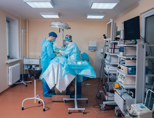 Group of surgeons in operating room with surgery equipment.