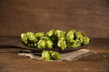 Beer brewing ingredients Hop cones in wooden bowl and wheat ears on wooden background. Beer brewery concept.