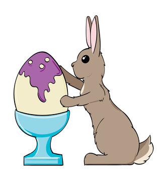 Bunny painting an Easter egg in an egg cup