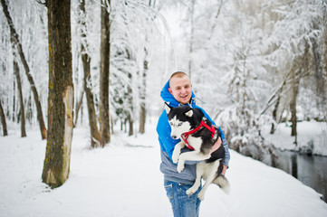 Fototapeta na wymiar Man with husky dog at winter snowy park.