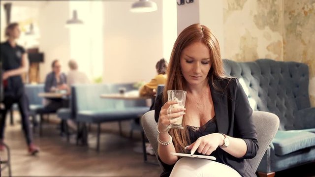 Young beautiful woman sitting with tablet in cafe
