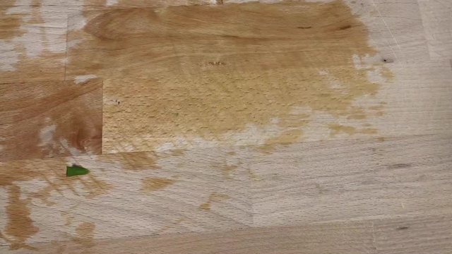 Time lapse close up of a Caucasian female hand cutting slices of green Italian taccola, a kind of pea (Pisum sativum), uncooked on a wooden cutting board in a kitchen with a knife.