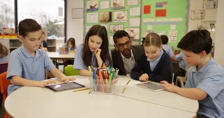 4K Happy young school children working on digital tablets in classroom with teacher helping out. Slow motion - Powered by Adobe