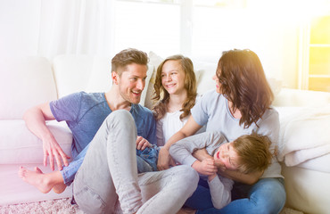 Obraz premium Familie sitzt vor der Couch im Wohnzimmer mit 2 Kindern