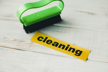 Cleaning house or office concept. Green cleaning brush and Cleaning inscription on a white wooden...