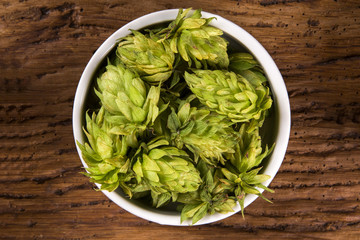 Beer brewing ingredients Hop cones in white bowl on wooden background. Beer brewery concept.