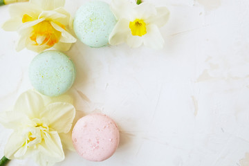 Traditional French blueberry strawberry cranberry macaroons dessert biscuits with beautiful flowers arrangement on white gray concrete textured background table top. Tasty but unhealthy food.