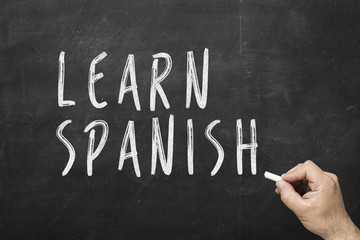 Fototapeta premium Human hand writing text on blackboard: Learn spanish