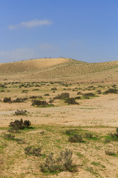 Hill at far in desert under blue sky