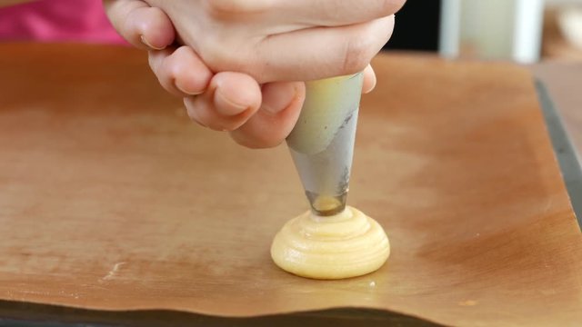 Bakery pastry chef Piping dough for cream puff or profiterole or choux creme on baking tray.