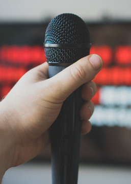 Man hand with karaoke microphone in front of TV.