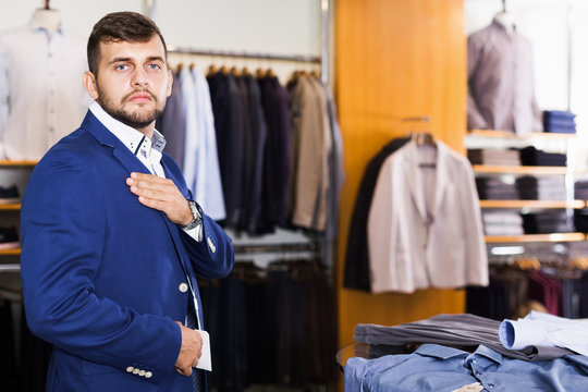 Man customer choosing jacket in men clothes store