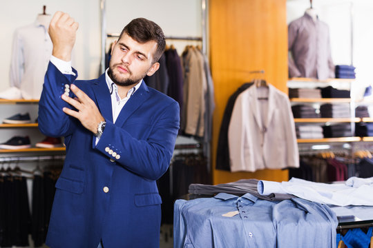 Smiling male shopper choosing fashion jacket