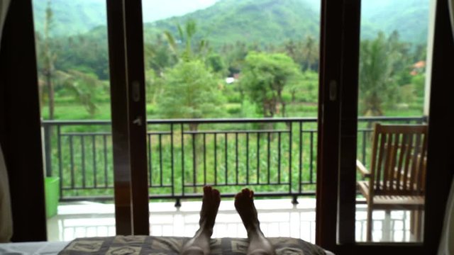 man falling on the bed in his hotel room with beautiful mountains view relax and enjoy his holiday vacation in tropical asian country, travel concept, vertigo effect