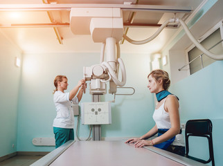 Radiologist and patient in a x-ray room. Classic ceiling-mounted x-ray system.