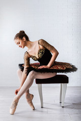 Fototapeta premium Portrait of Young Beautiful perfect ballerina sitting on chair indoors