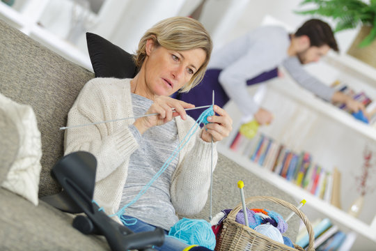 woman knitting while a man is cleaning