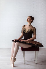 Fototapeta premium Portrait of Young Beautiful perfect ballerina sitting on chair indoors