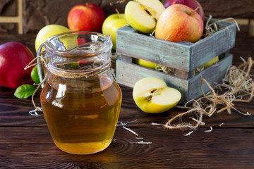 Fresh fruity apple juice and ripe apples on a wooden table. The concept of nutrition for superfoods and health or detoxification.