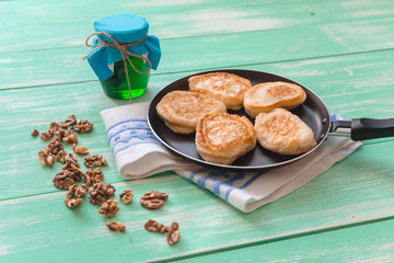 pan with pancakes, nuts and honey on a wooden table