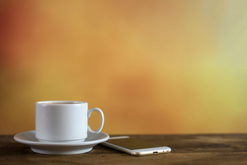 White cup of coffee with phone on colorful background. With copy space
