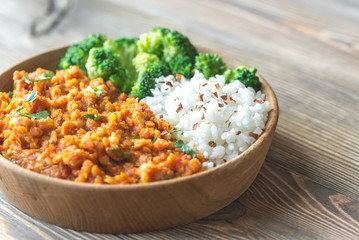 Bowl of red lentil curry with white rice and broccoli