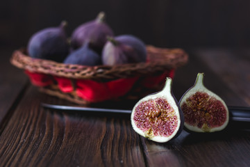 Halves of fresh ripe fig fruits with basket in a background.