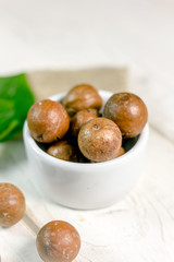 White ceramic bowl with macadamia nuts over the wooden table.