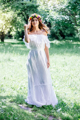 Young bride in a wedding dress staying on a forest.