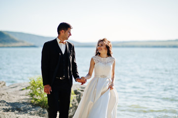 Wedding couple at breathtaking landscape with rock and lake.