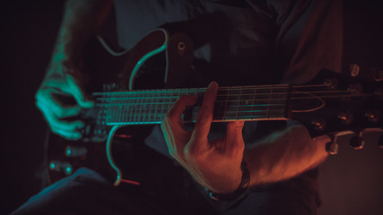 A man plays electric guitar, cyan and red lighting