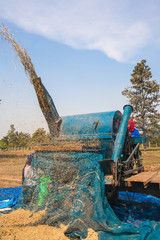 A group of Thai farmers use a machine to separate rice kernels, in a rice field in northeastern Thailand during the harvest period