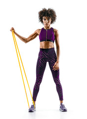 Strong girl using a resistance band in her exercise routine. Young african girl performs fitness exercises on white background. Strength and motivation