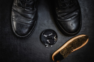 Men's military boots rme shoes, brush and shoe polish against a dark background flat lay top view 