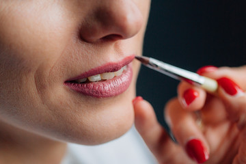 Process of making makeup. Make-up artist putting lipstick on lips