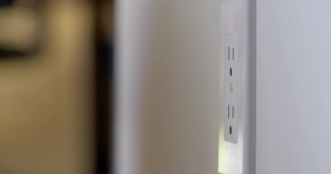 Woman's hand unplugs an electric cord from a wall outlet in the United States. Recorded in 4K with dolly move from right to left.