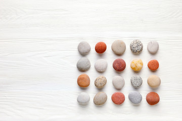 pattern of colored pebbles on white wooden background. Flat lay, top view