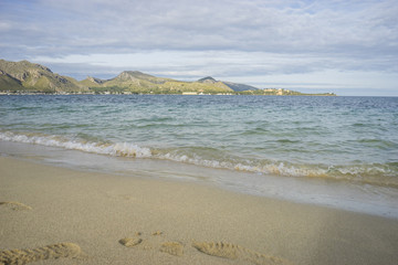 Peaceful Mediterranean scene, shore of the Mediterranean Sea with barefoot footprints of people in summer