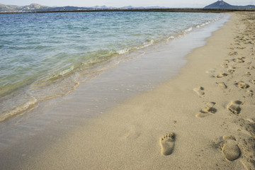 Mediterranean scene, shore of the Mediterranean Sea with barefoot footprints of people in summer