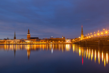 Obraz premium Skyline of old town of Riga seen across the river Daugava with the stone bridge at night.