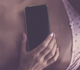 Woman with cellphone in bed - texting addiction.
