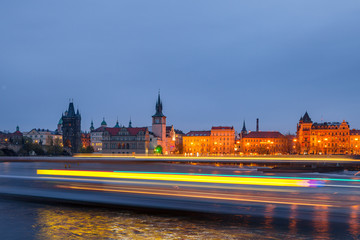 Fototapeta na wymiar View of motion blurred lights of cruise ship in front of night old town of Prague and with reflection in Vltava River